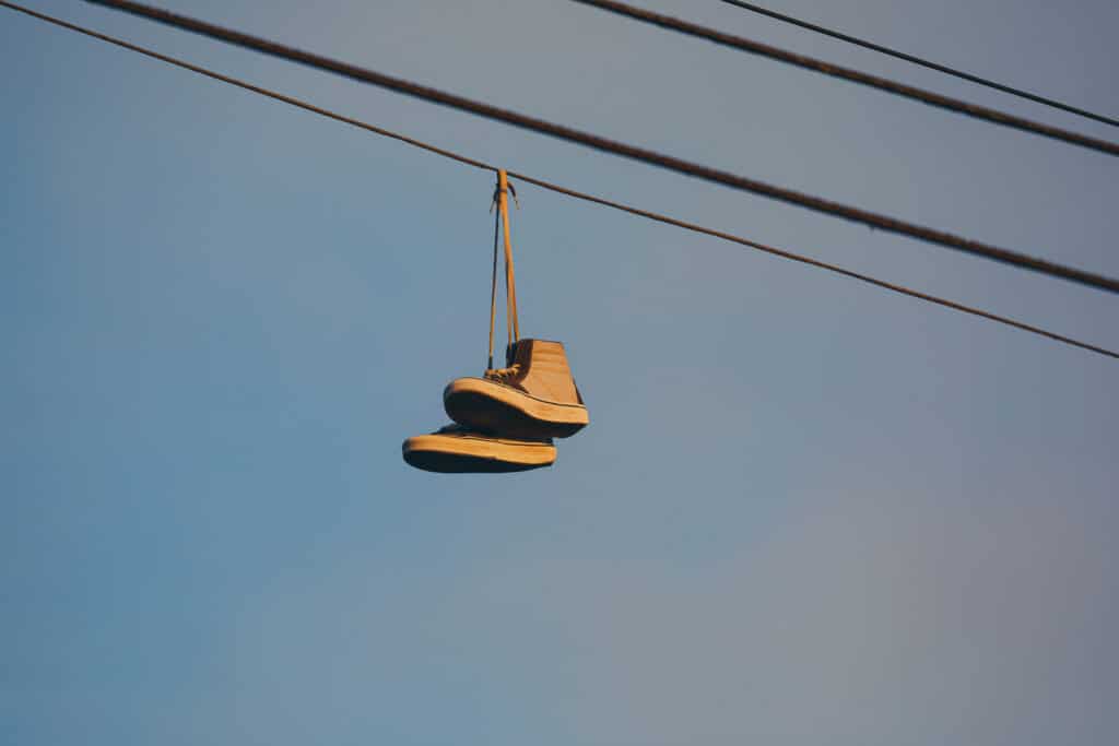 Close up of old sneakers hanging on a powerline in the evening glow