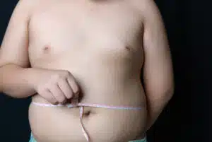 obese fat boy measuring tape of stomach isolated on black background, healthy and lose weight